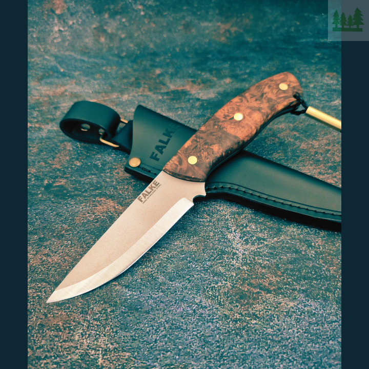 Falke Scandi N690 w studiu z pochwą i rękojeścią Profesjonalne ujęcie noża Falke Scandi N690 ze stabilizowanym czeczotem brzozy i przekładką G10, w komplecie z czarną skórzaną pochwą, na neutralnym tle studyjnym.